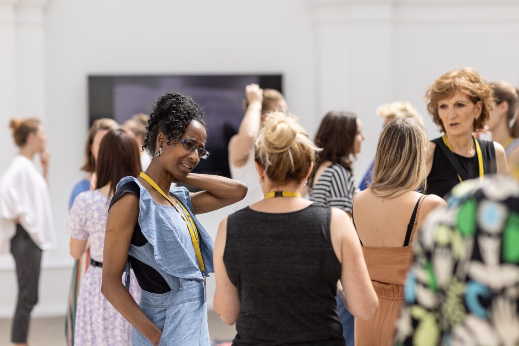 A group of people speaking in a bright gallery space